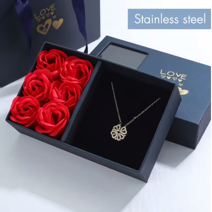 Coffret cadeau ouvert : roses décoratives et collier trèfle doré